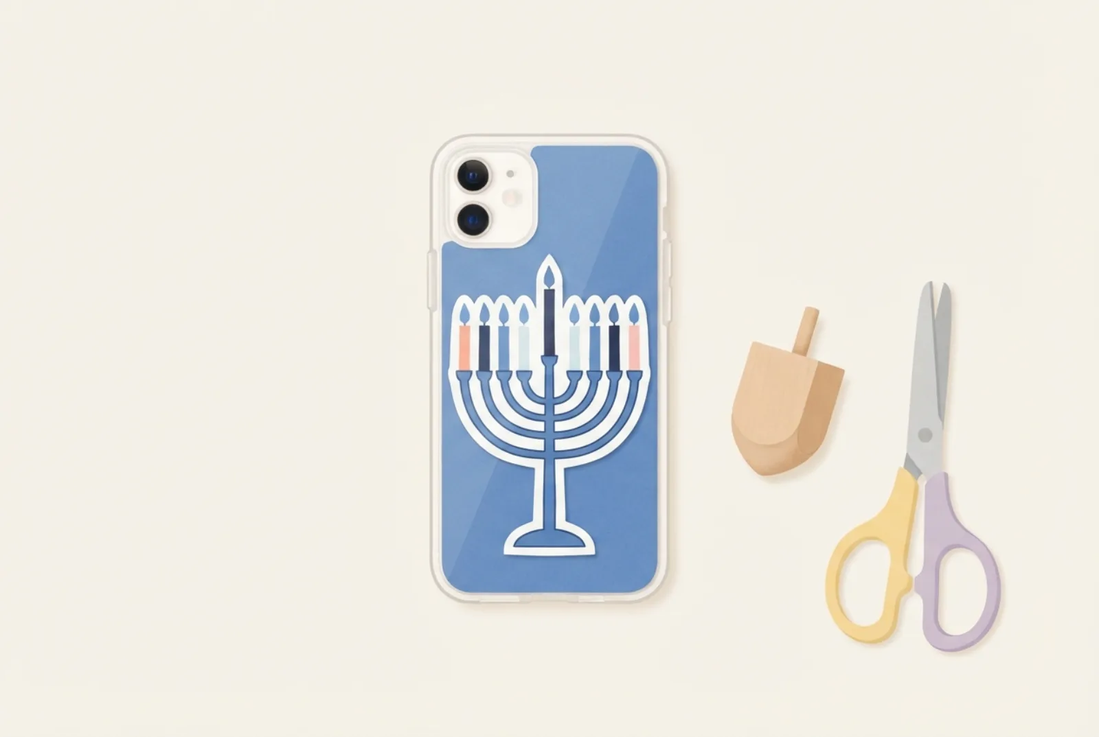A clear phone case holding a blue and white insert with a hand-drawn nine-branch menorah, next to a wooden spinning top and a pair of scissors